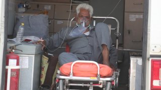 In this April 22, 2021, file photo, a COVID-19 patient waits inside an ambulance to be attended to and admitted into a dedicated COVID-19 government hospital in Ahmedabad, India.