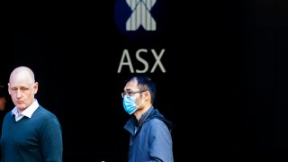 A man in a mask is seen in front of The Australian Stock Exchange logo on March 13, 2020 in Sydney, Australia.