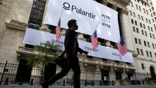 A pedestrian passes a banner displaying Palantir Technologies signage during the company’s initial public offering (IPO) in front of the New York Stock Exchange (NYSE), Sept. 30, 2020.