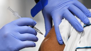 A health care professional administers a shot to a patient.