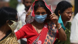 A woman wearing mask as a precaution against Covid-19 stands in a crowded area near India Gate, in New Delhi on March 19, 2021 as coronavirus cases continue to increase across India.