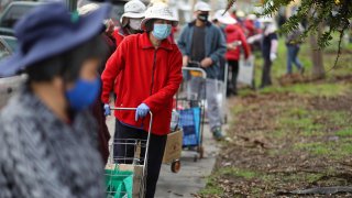 OAKLAND, CA – FEBRUARY 9: Local residents line up for food distribution at the Vietnamese American Community Center of the East Bay on Tuesday, Feb. 9, 2021, in Oakland, Calif. The organization”u2019s building in Clinton Park was severely damaged over the weekend by a fire believed to be started in a homeless encampment next to the community center. (Aric Crabb/MediaNews Group/East Bay Times via Getty Images)