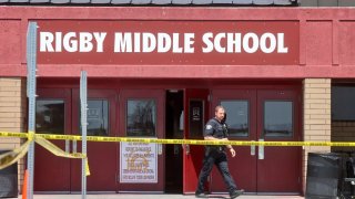 Photo of officer exiting Rigby Middle School with caution tape