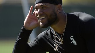 White Sox infielder Yoan Moncada smiles and puts his hand to his ear, gesturing to to a teammate during spring training