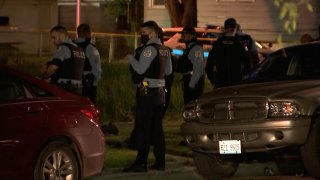 Chicago police officers, wearing blue shirts and black vests, stand near the scene of a crash in Chicago's Englewood neighborhood