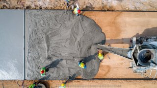 Construction workers pouring wet concrete on a road. With 20% of the planned infrastructure bill, or $110 billion, dedicated for the construction of roads and bridges, small constructions firms are hoping for a long-term boom in business.