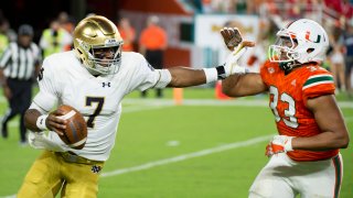 Notre Dame Quarterback Brandon Wimbush (7) runs with the ball under pressure from University of Miami Hurricanes Defensive Lineman Trent Harris (33) during the college football game between the Notre Dame Fighting Irish and the University of Miami Hurricanes on November 11, 2017 at the Hard Rock Stadium in Miami Gardens, Florida.