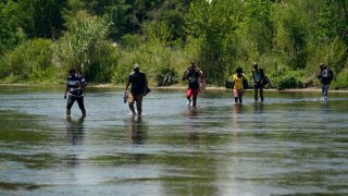 A group of migrants walk across the Rio Grande river.