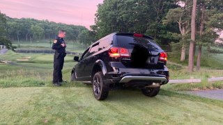 An officer observers an SUV stuck on the grass at Brae Burn Country Club in Newton
