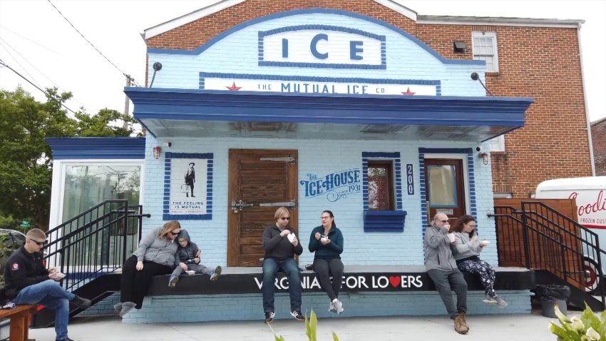 Blue building with sign reading "ICE" and people eating dessert on porch.