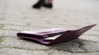 A woman walking away after dropping her wallet on the ground.