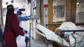 An 81-year-old African American COVID-19 patient is brought from the emergency room into the ICU ward at Roseland Community Hospital on December 14, 2020 in Chicago, Illinois.