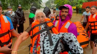 A National Disaster Response Force personnel carries an elderly woman through water.