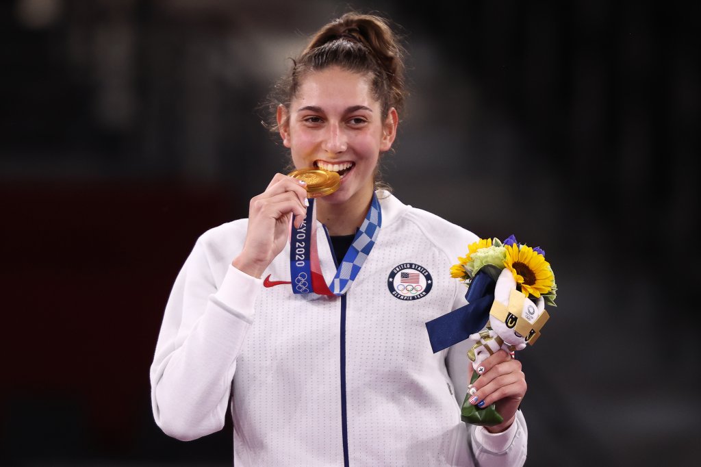 Gold medallist Anastasija Zolotic of the United States bites her medal at a victory ceremony for the women's -57kg taekwondo event during the Tokyo 2020 Summer Olympic Games, at the Makuhari Messe convention center.