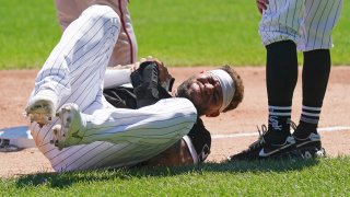 White Sox star Yoan Moncada lays on the ground, holding his right hand after suffering an injury on the basepaths during a game against the Twins