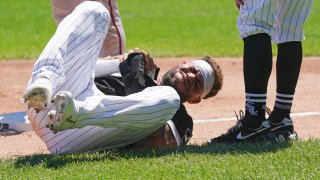 White Sox star Yoan Moncada lays on the ground, holding his right hand after suffering an injury on the basepaths during a game against the Twins
