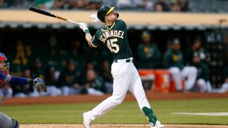 Frank Schwindel, shown in a green Oakland Athletics jersey and green helmet, swings at a pitch during a game against the Rangers