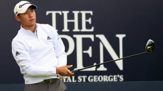 American golfer Collin Morikawa, wearing a white shirt and a white hat, watches a tee shot during the Open Championship on July 15