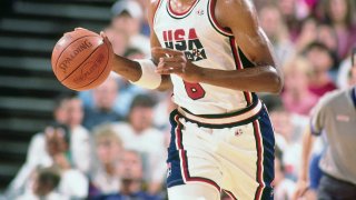 Scottie Pippen is seen in a red, white and blue Team USA jersey and shorts, dribbling a ball during the 1992 Olympics in Spain