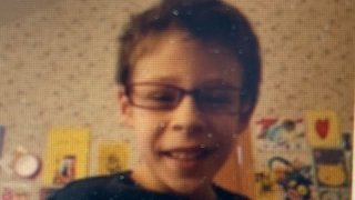 A missing Aurora child, wearing glasses and a black t-shirt, is featured in this image