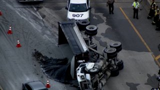 A dump truck sits on its side, with black gravel spilling onto a Chicago expressway on July 22, 2021