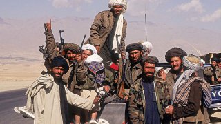 Taliban fighters with a vehicle on a highway in Afghanistan.