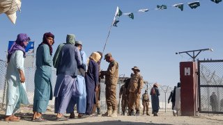 Pakistani soldiers check documents of stranded Afghan nationals returning to Afghanistan at the Pakistan-Afghanistan border crossing point in Chaman on August 14, 2021
