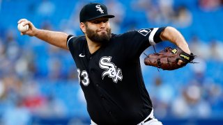 Lance Lynn of the Chicago White Sox, wearing a black White Sox jersey with white lettering and numbers, along with a black baseball cap, throws a pitch against the Blue Jays