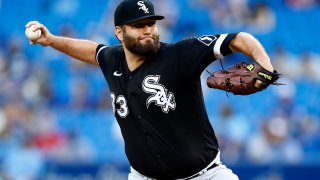 Lance Lynn of the Chicago White Sox, wearing a black White Sox jersey with white lettering and numbers, along with a black baseball cap, throws a pitch against the Blue Jays