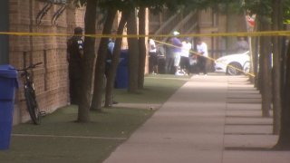 Chicago police stand near yellow crime scene tape and a sidewalk on the city's Near North Side after a shooting