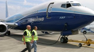 Boeing employees walk by a new Boeing 737-900 at Boeing Field in Seattle.