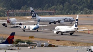 Planes line-up to take a turn onto the center runway for take-off at Seattle-Tacoma International Airport Monday, Aug. 13, 2018, in SeaTac, Wash. The plane at center left, an Alaska Airlines Q400 turboprop airplane, is the same model of aircraft stolen from the airport by an airline ground agent on Friday, which later crashed into crashed into a small island in the Puget Sound, killing the man.