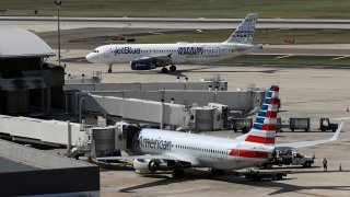 FILE - A JetBlue Airbus A320 taxis to a gate Wednesday, Oct. 26, 2016, after landing as an American Airlines jet is seen parked at its gate at Tampa International Airport in Tampa, Fla. The Justice Department is suing to stop American Airlines and JetBlue from coordinating their flights in the Northeast. Government antitrust lawyers said Tuesday, Sept. 21, 2021, that the deal between the two airlines will reduce competition and lead to higher fares.