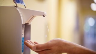 Close-up of a male nurse cleaning hands with sanitizer in hospital. Medical professional cleaning hands with antiseptic fluid.