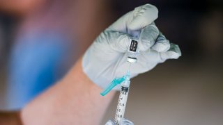 A nurse fills a syringe with a dose of BioNTech, Pfizer COVID-19 vaccine.