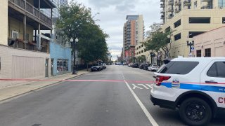 A photo shows West Division Street in Chicago during a SWAT situation, with a white and blue police SUV and red crime scene tape