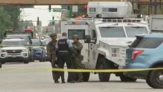 Three members of a Chicago SWAT team stand next to a white armored vehicle on West Division Street in Chicago
