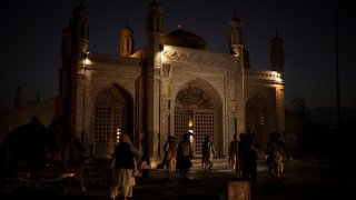 Taliban fighters walk at the entrance of the Eidgah Mosque after an explosion in Kabul, Afghanistan