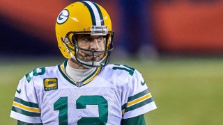 Aaron Rodgers stands at Soldier Field, wearing a yellow Packers helmet and a white jersey with green letters and numbers