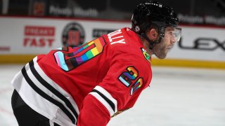 Blackhawks forward Brett Connolly, wearing a red jersey with a rainbow color pattern on the numbers, waits for his turn to shoot during warmups before a game