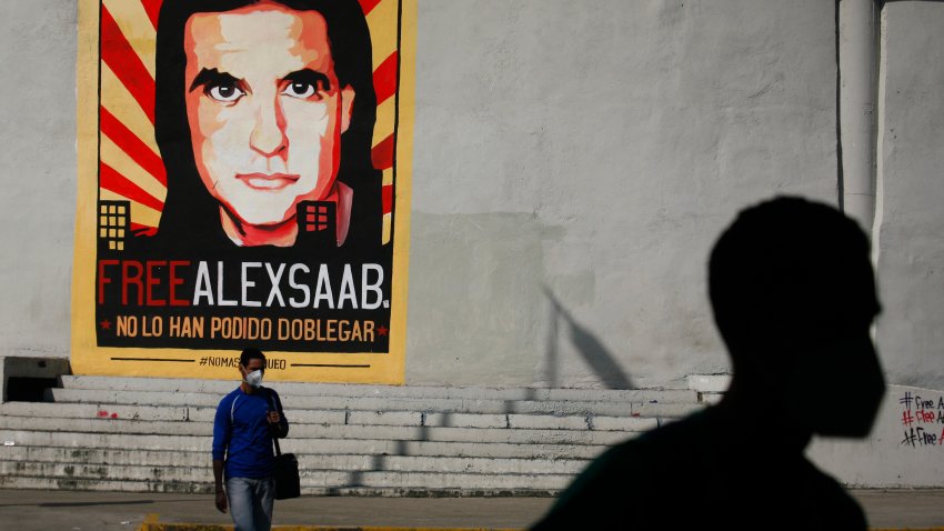 People walk past graffiti in favor of the release of Colombian businessman Alex Saab, amidst the Coronavirus pandemic, on the west side of the city in Caracas, Venezuela on September 8, 2021. (Photo by Javier Campos/NurPhoto via Getty Images)