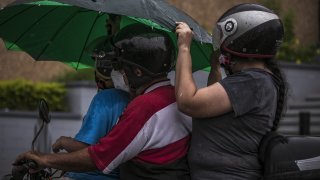 People ride a motorcycle under the rain before the arrival of Tropical Storm Pamela in Culiacan