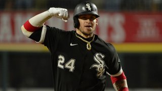 Yasmani Grandal, wearing a black White Sox jersey and black helmet with white lettering, pumps his fist and rounds the bases after hitting a home run against the Astros in the American League Division Series