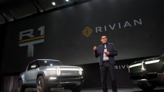 RJ Scaringe, founder and chief executive officer of Rivian Automotive Inc., unveils the R1T electric pickup truck, left, and R1S electric sports utility vehicle (SUV) during a reveal event at AutoMobility LA ahead of the Los Angeles Auto Show in Los Angeles, California.