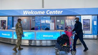 Military personal speak with travellers as they arrive at terminal 4 at JFK International airport in New York on December 22, 2020.