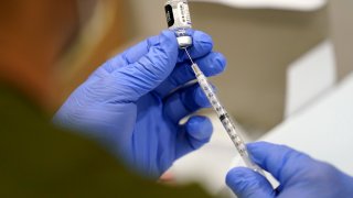 FILE - A healthcare worker fills a syringe with the Pfizer COVID-19 vaccine at Jackson Memorial Hospital on Oct. 5, 2021, in Miami. U.S. regulators have opened up COVID-19 booster shots to all and more adults, Friday, Nov. 19, letting them choose another dose of either the Pfizer or Moderna vaccine.