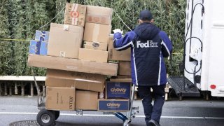 A driver for an independent contractor to FedEx Corp. loads packages on a cart during Cyber Monday in the Hell’s Kitchen neighborhood of New York, on Monday, Nov. 29, 2021.