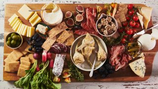 A variety of cheeses, spreads and cured meats are displayed on a graze board