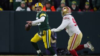 Quarterback Aaron Rodgers #12 of the Green Bay Packers looks to pass as defensive tackle D.J. Jones #93 of the San Francisco 49ers applies pressure during the 1st quarter of the NFC Divisional Playoff game at Lambeau Field on January 22, 2022 in Green Bay, Wisconsin.