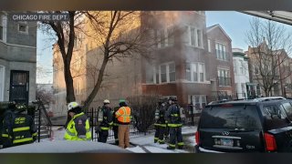 Chicago firefighters stand outside of a three-story brick residence during a West Town fire